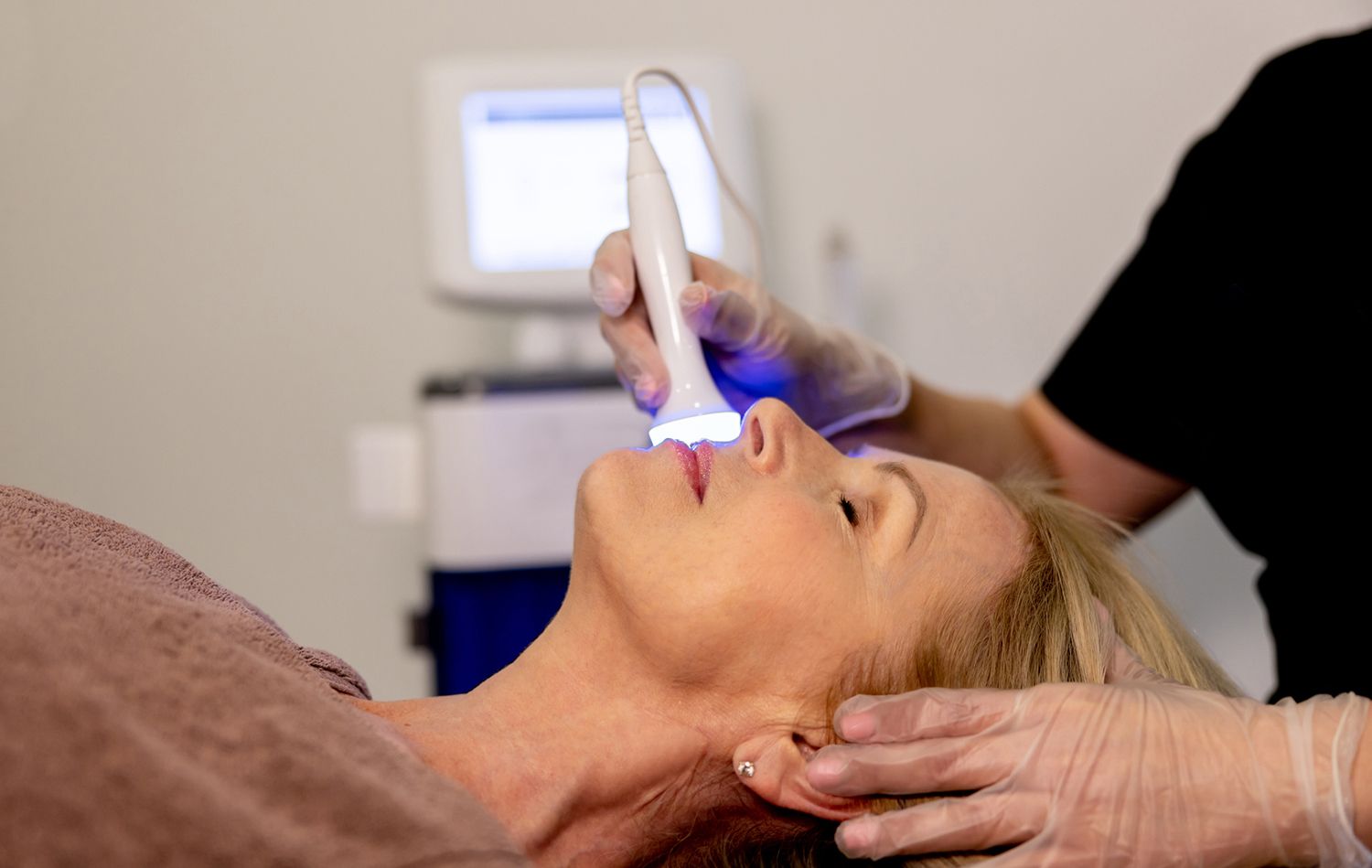 Woman receiving a skin treatment with a blue-light device.