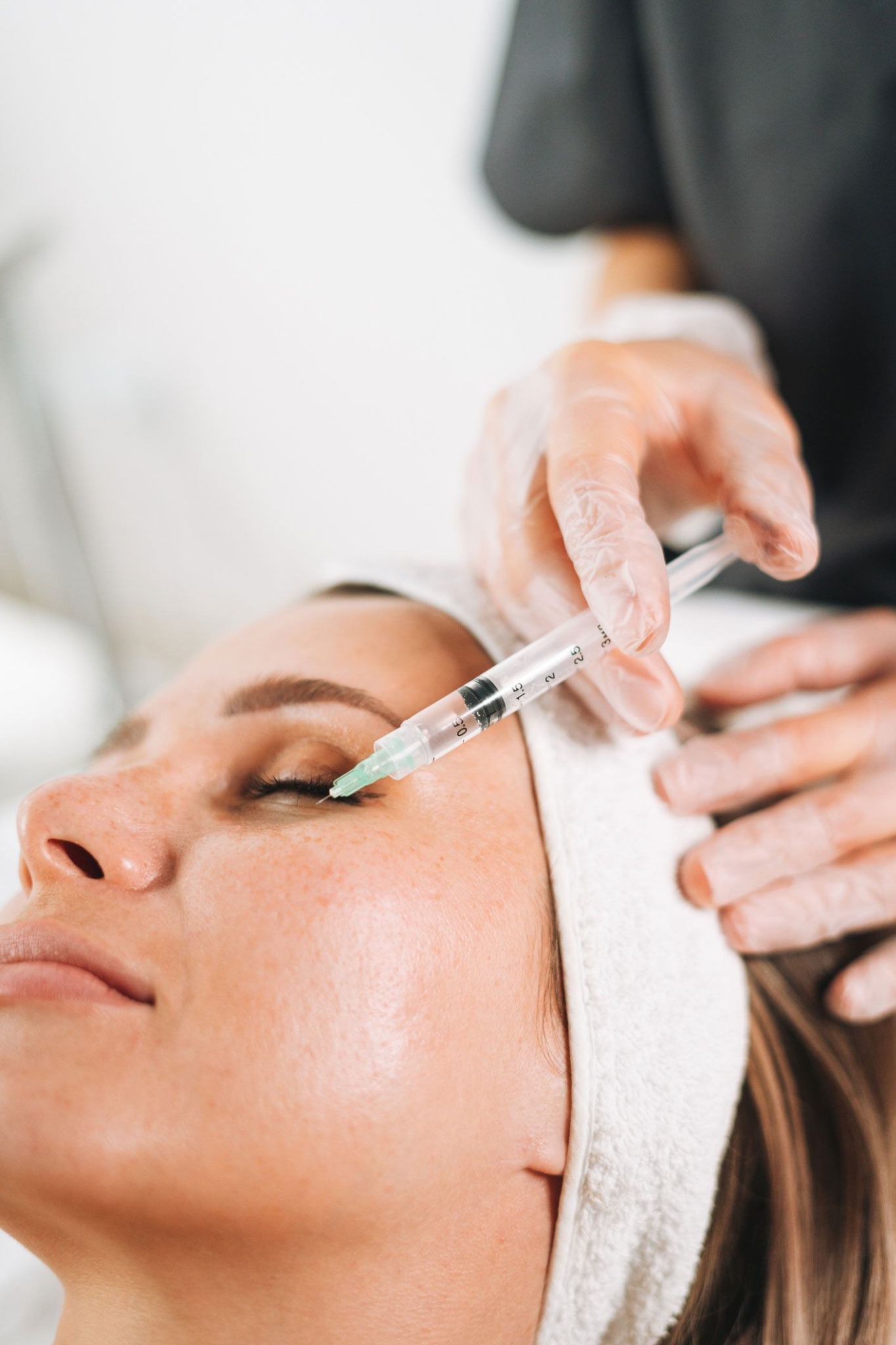 A person receiving an under-eye injection at a medical office.