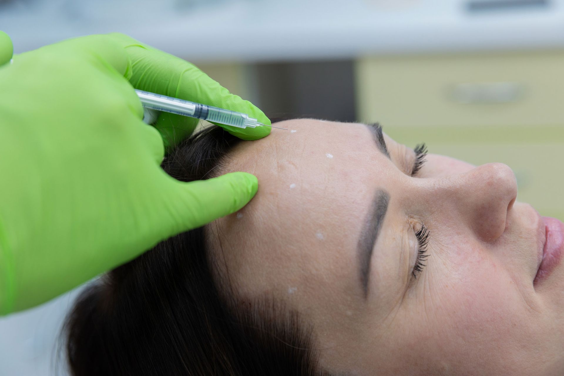 Person receiving a facial injection in a medical setting.